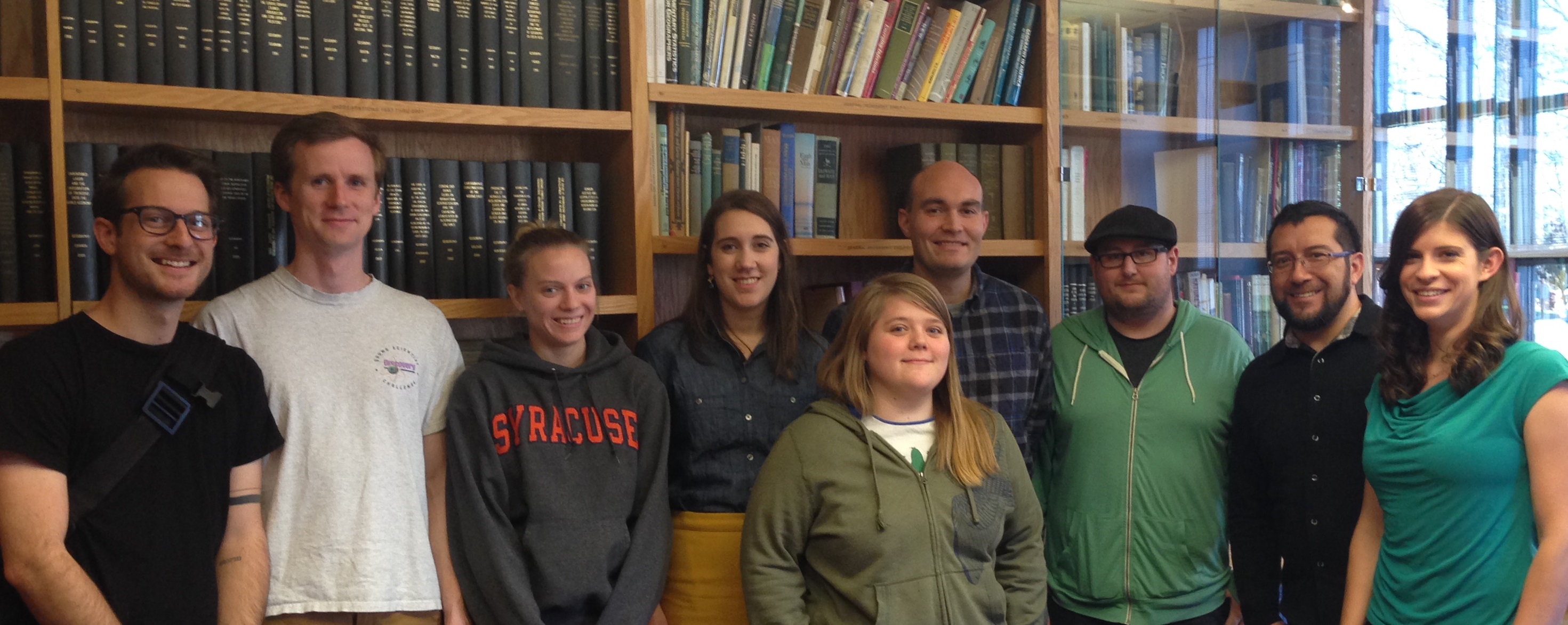 Syracuse University Geography Graduate Students standing in the James Library, looking happy.